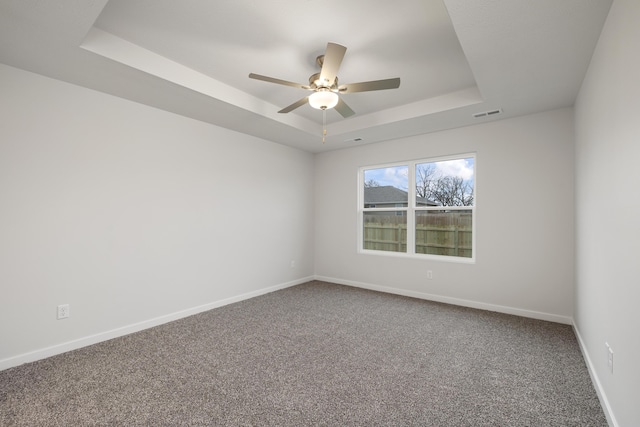 empty room featuring baseboards, a raised ceiling, ceiling fan, and carpet flooring