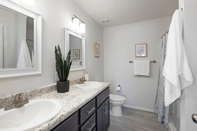 full bathroom with visible vents, a sink, a textured ceiling, and toilet