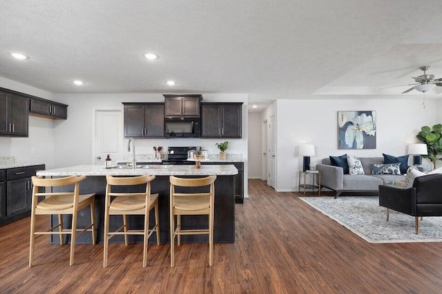 kitchen with open floor plan, black appliances, dark wood finished floors, and light countertops