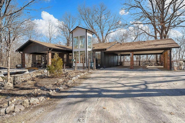 view of front of home featuring driveway, a carport, and brick siding