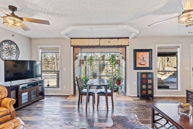 living area with ceiling fan, a textured ceiling, baseboards, and wood finished floors