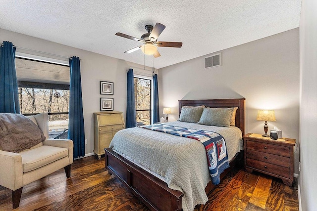 bedroom featuring dark wood-style floors, a ceiling fan, visible vents, and a textured ceiling