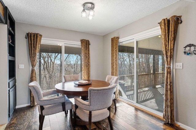 dining space with a textured ceiling, wood finished floors, and baseboards