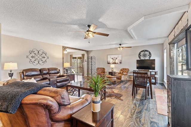 living area with wood-type flooring, ceiling fan, and a textured ceiling