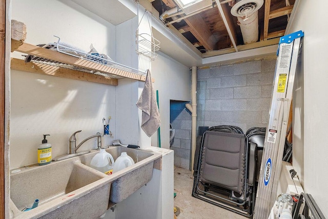 kitchen with concrete block wall, unfinished concrete floors, and a sink