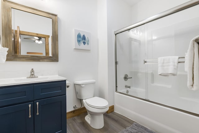 bathroom featuring bath / shower combo with glass door, toilet, vanity, wood finished floors, and baseboards