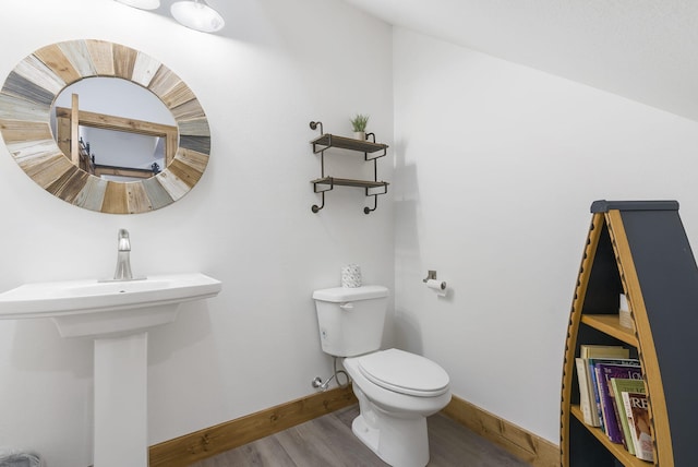 bathroom with baseboards, toilet, and wood finished floors