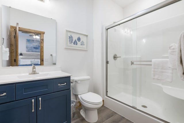 bathroom featuring toilet, a stall shower, wood finished floors, and vanity