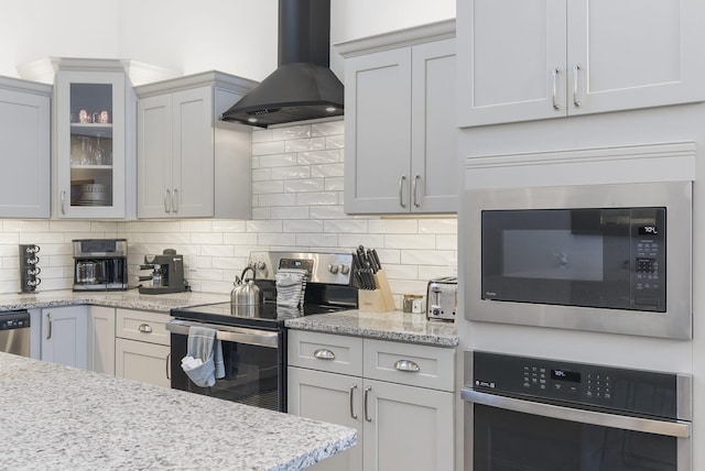 kitchen featuring stainless steel appliances, extractor fan, glass insert cabinets, and decorative backsplash