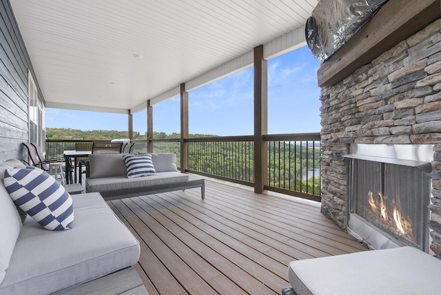 wooden terrace with an outdoor living space with a fireplace