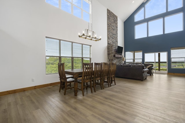 dining area featuring lofted ceiling, a notable chandelier, a fireplace, wood finished floors, and baseboards