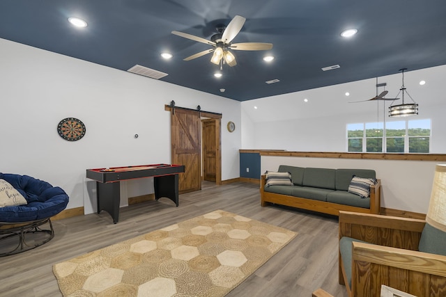 recreation room with a barn door, baseboards, visible vents, ceiling fan, and wood finished floors