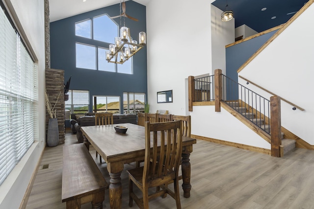 dining area featuring a notable chandelier, visible vents, stairway, a high ceiling, and wood finished floors