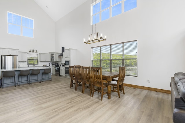 dining area featuring a chandelier, vaulted ceiling, light wood-type flooring, and baseboards