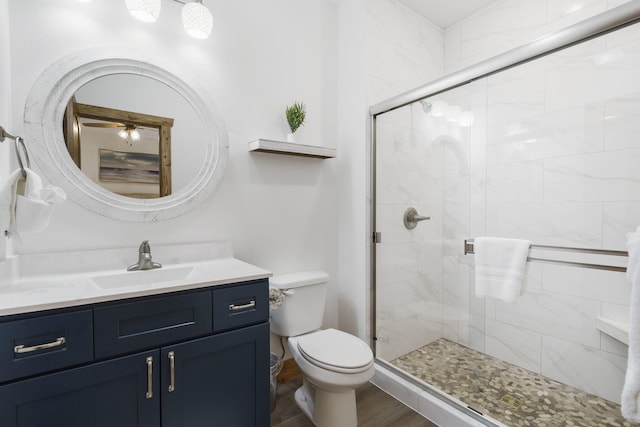 full bathroom featuring toilet, a stall shower, wood finished floors, and vanity