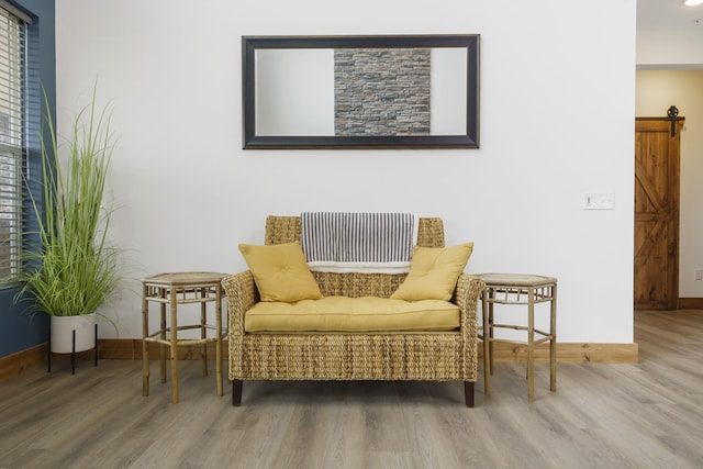 sitting room with wood finished floors, baseboards, and a barn door