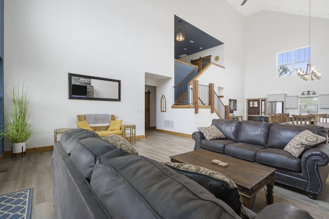 living area with visible vents, stairway, wood finished floors, a chandelier, and baseboards