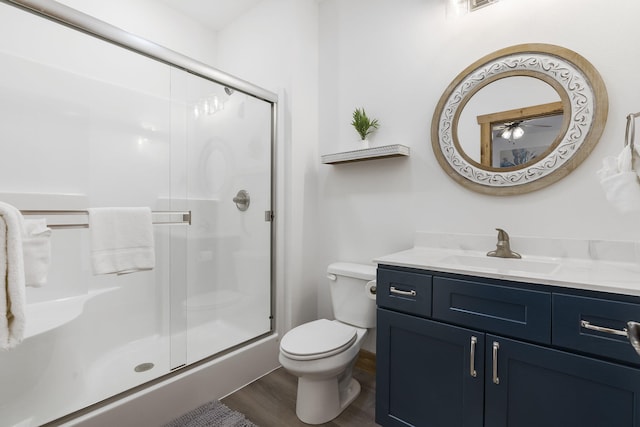 full bath featuring vanity, wood finished floors, a shower stall, and toilet