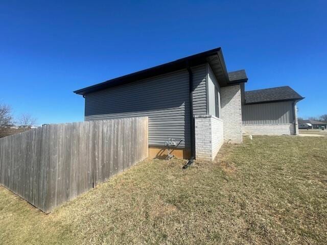 view of home's exterior with a yard, fence, and brick siding