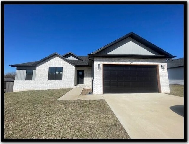 view of front of house featuring an attached garage, a front lawn, concrete driveway, and brick siding