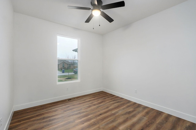 spare room featuring dark wood-style flooring, visible vents, and baseboards