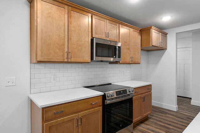 kitchen featuring tasteful backsplash, stainless steel appliances, dark wood finished floors, and light countertops