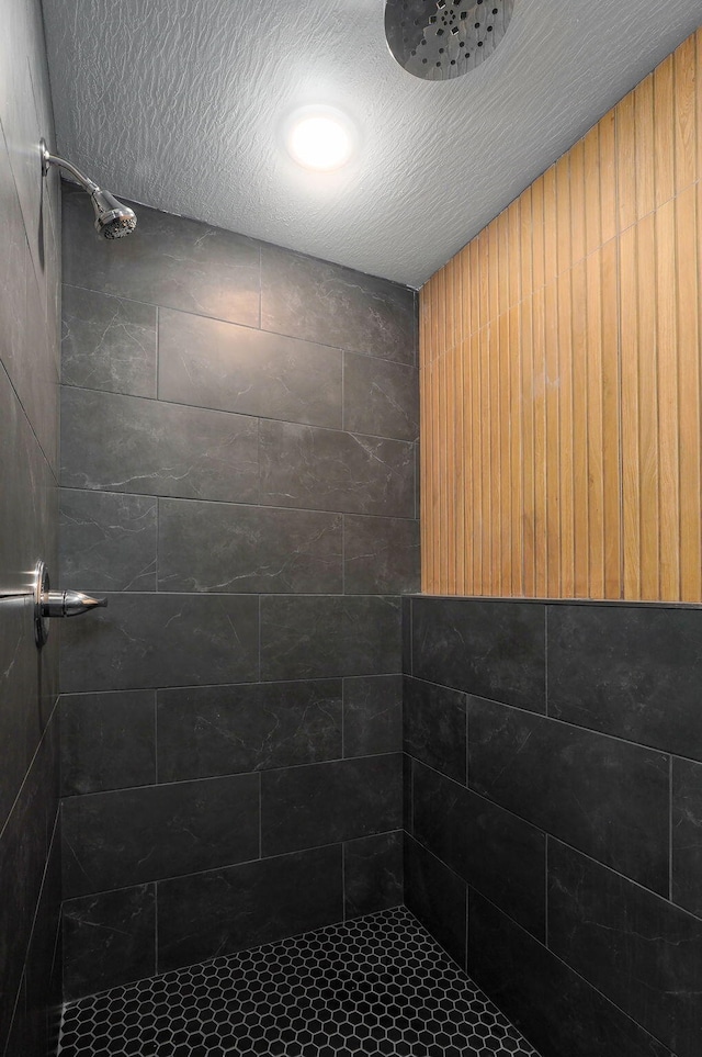 bathroom with a textured ceiling and a tile shower