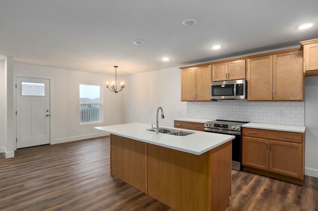 kitchen with appliances with stainless steel finishes, dark wood-type flooring, a sink, and tasteful backsplash