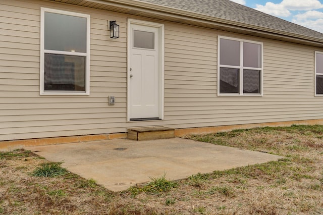 property entrance with a patio area and a shingled roof