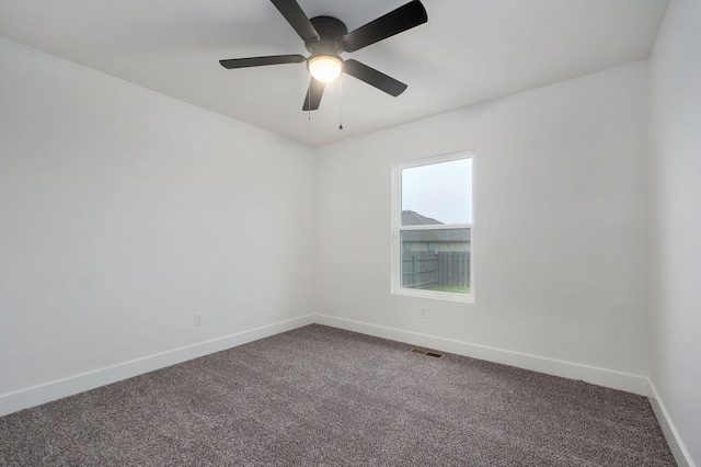 empty room featuring visible vents, baseboards, dark carpet, and a ceiling fan