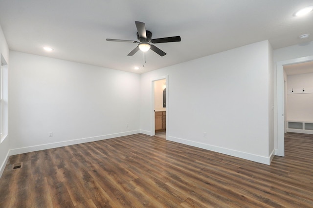 empty room with dark wood-style floors, visible vents, and baseboards