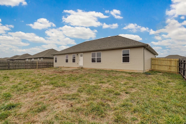 rear view of property with a lawn and a fenced backyard