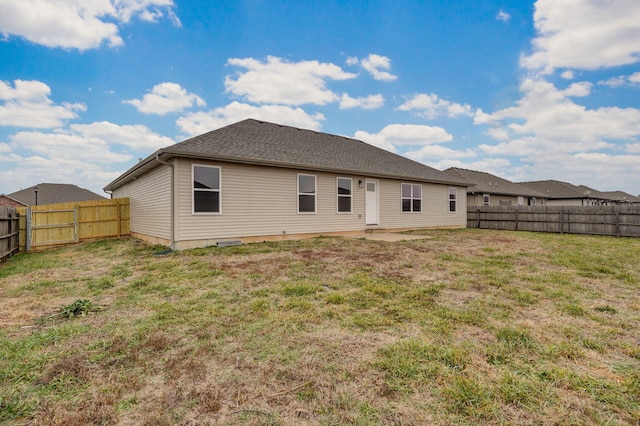 rear view of house featuring a lawn and a fenced backyard