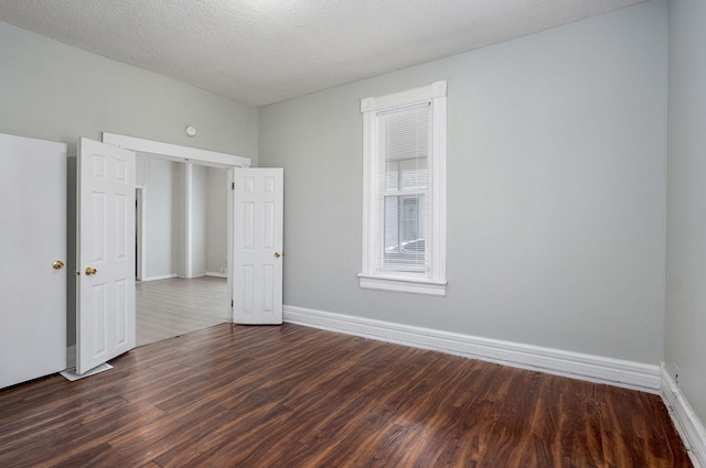 spare room with dark wood-style floors, baseboards, and a textured ceiling