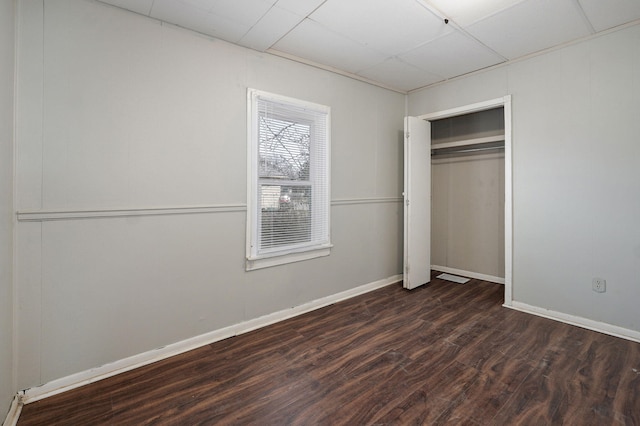 unfurnished bedroom featuring dark wood-style floors, a closet, and baseboards