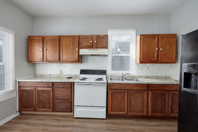 kitchen with light wood-style floors, black refrigerator with ice dispenser, white electric range, under cabinet range hood, and a sink