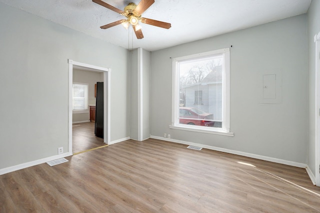 spare room with light wood-style floors, visible vents, and baseboards