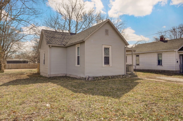 view of property exterior with roof with shingles, a yard, and fence