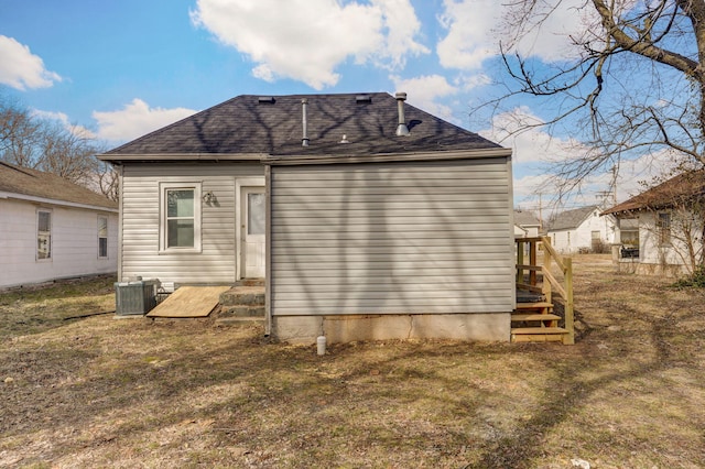 back of property with roof with shingles, a lawn, and central AC unit