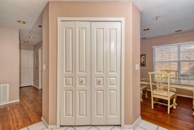 corridor featuring visible vents, a textured ceiling, and light wood finished floors