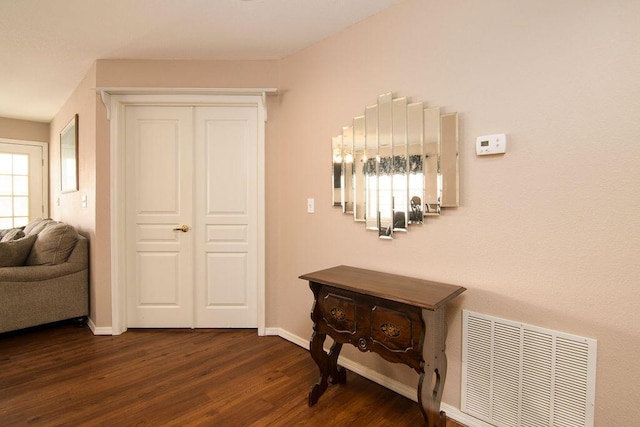 hall featuring dark wood-style floors, visible vents, and baseboards