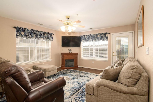living area featuring plenty of natural light, a fireplace, ceiling fan, and wood finished floors