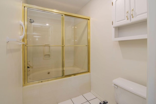 bathroom featuring tile patterned flooring, baseboards, toilet, and bath / shower combo with glass door