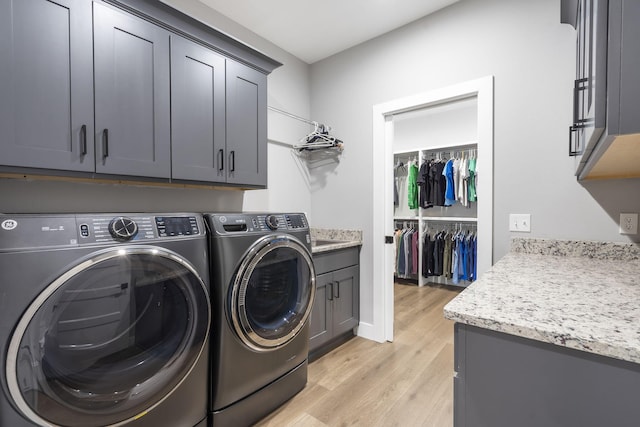 washroom featuring light wood-type flooring, cabinet space, and washer and clothes dryer