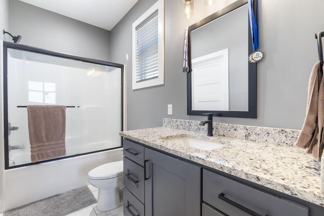 full bath with toilet, combined bath / shower with glass door, vanity, and a healthy amount of sunlight