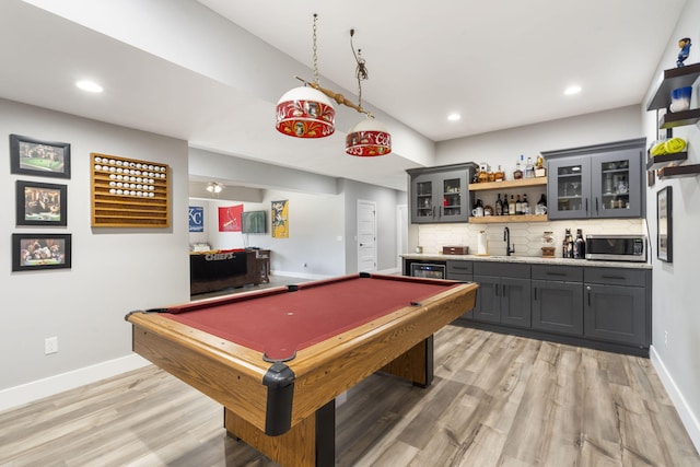 rec room with baseboards, light wood finished floors, a sink, and wet bar