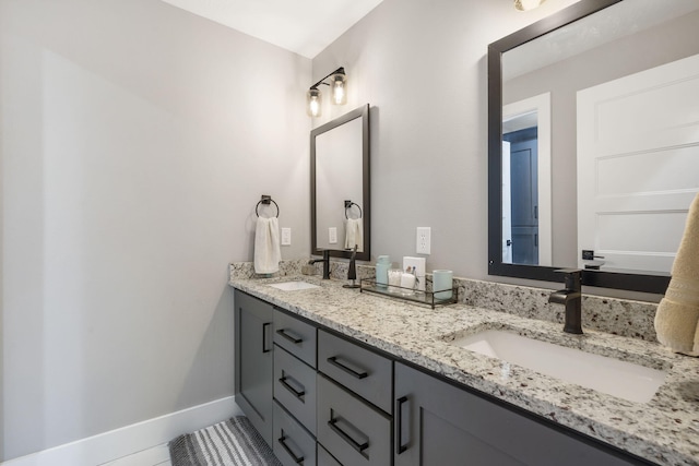 bathroom featuring double vanity, a sink, and baseboards