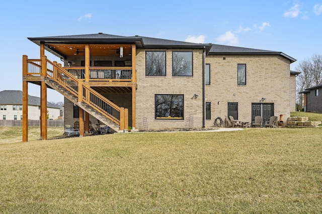 rear view of property with brick siding, a wooden deck, stairs, and a yard