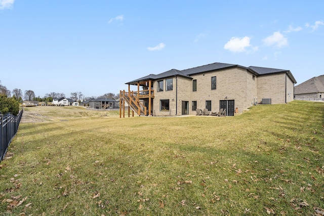 rear view of house featuring a deck, cooling unit, brick siding, stairs, and a lawn