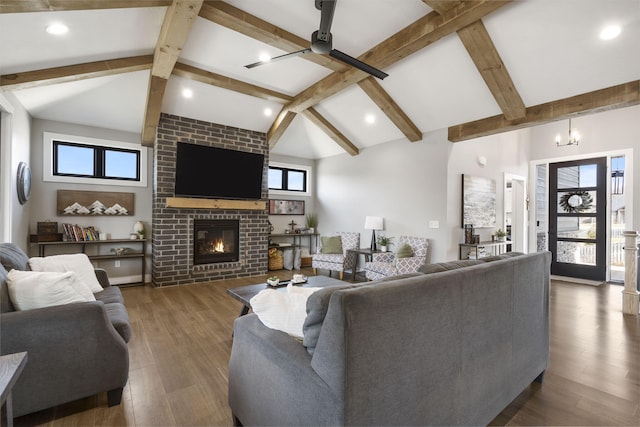 living area featuring vaulted ceiling with beams, a fireplace, ceiling fan, and wood finished floors